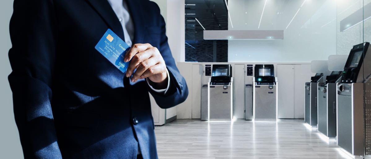 businessman holding credit card in front of transaction terminals